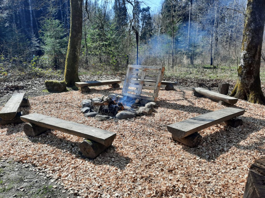 Bancs en bois autour du foyer du Refuge sur leur manteau de copeaux fournis par Spycher Broyage Sàrl